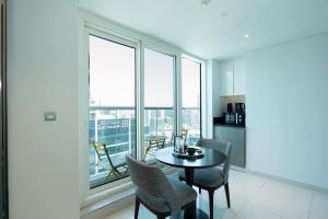 Business Bay centrally located Cozy Studio في دبي: غرفة طعام مع طاولة وكراسي ونوافذ
