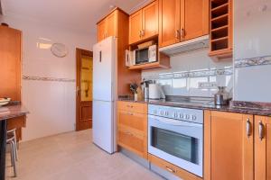 a kitchen with wooden cabinets and a white refrigerator at Ático con 2 terrazas, 25m2 cada una By urban hosts in Górliz-Elexalde