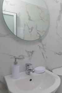 Baño blanco con lavabo y espejo en Vila Kristian en Ksamil