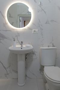 ein weißes Badezimmer mit einem Waschbecken und einem Spiegel in der Unterkunft Vila Kristian in Ksamil