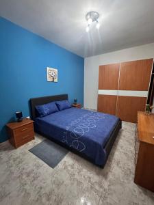 a bedroom with a bed and a blue wall at Marsaskala Sea Side Retreat in Marsaskala