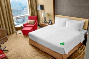 a hotel room with a large bed and a red chair at Millennium Plaza Doha in Doha