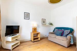 ein Wohnzimmer mit einem Sofa und einem TV in der Unterkunft A Tranquil One-Bedroom Flat near Brockwell Park in London