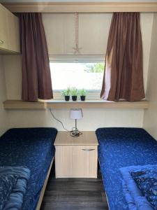 twee bedden in een kleine kamer met een raam bij RBR 1252 - Beach Resort Kamperland in Kamperland