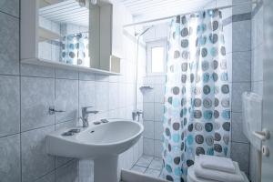 a white bathroom with a sink and a shower curtain at Litsa Mare Apartments in Agia Pelagia