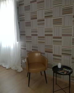 uma cadeira e uma mesa num quarto com uma parede em Arina Home -Aeroporto Fontanarossa- em Catânia