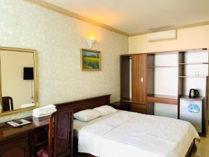 1 dormitorio con cama, escritorio y espejo en Lam Son Hotel, en Vung Tau