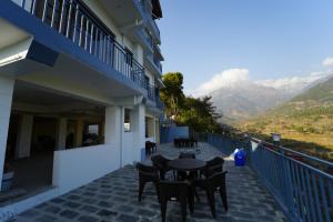 a balcony with a table and chairs and mountains at Prem BnB Palampur in Pālampur