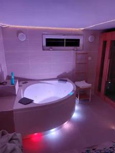 łazienka z wanną w pokoju z fioletowymi światłami w obiekcie Maison village vignoble avec balnéo w mieście Mailly-Champagne