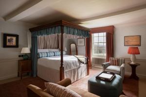 a bedroom with a canopy bed and a chair at Cavendish Hotel in Baslow