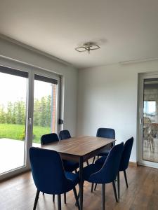 a dining room with a wooden table and blue chairs at Villa Ozoni 2 - Jezerc in Ferizaj