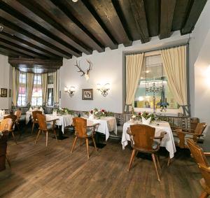 uma sala de jantar com mesas e cadeiras brancas em Sporthotel Igls em Innsbruck