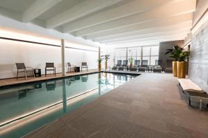 a pool in a building with chairs and tables at Sporthotel Igls in Innsbruck