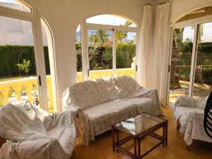 un soggiorno con divano, tavolo e finestre di Laura a Els Poblets