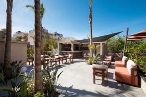 eine Terrasse mit Tischen, Stühlen und Palmen in der Unterkunft Cosmeen Lifestyle Boutique Stay in Hersonissos