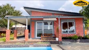 a small red brick house with a bench in front at Villa Mutiara Cawene in Gunungpicung