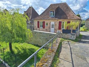 una casa con porte rosse e un muro di pietra di Gite Le Pigeonnier a Miers
