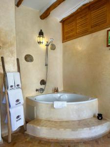 a bathroom with a bath tub with a shower and towels at Riad Baladin in Essaouira