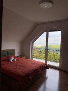a bedroom with a red bed and a large window at Villa Ozoni 2 - Jezerc in Ferizaj