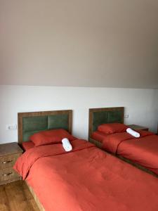 two beds in a bedroom with red sheets at Villa Ozoni 2 - Jezerc in Ferizaj