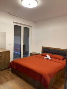 a bedroom with a large bed with a red bedspread at Villa Ozoni 2 - Jezerc in Ferizaj