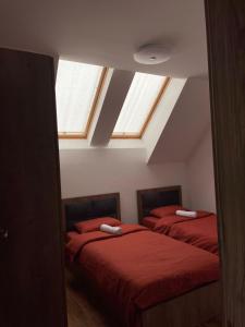 una camera mansardata con due letti con lenzuola rosse di Villa Ozoni 2 - Jezerc a Ferizaj
