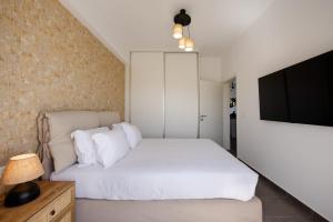 um quarto com uma cama branca e uma televisão de ecrã plano em FN Suites em Monolithos