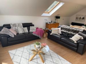 a living room with two black couches and a table at Loughview Lodge in Whitehead