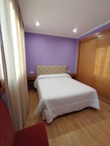 una camera con letto bianco e pareti viola di Casa o cocho Vigo Mos a Mos