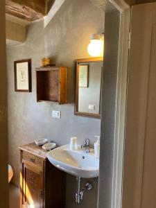 y baño con lavabo y espejo. en IL PICCINO 29, Esperienza Romantica in Borgo...., en Montescudaio