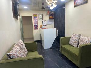 una sala d'attesa con due sedie verdi e un bancone di Hotel Kaushambi Grand a Ghaziabad