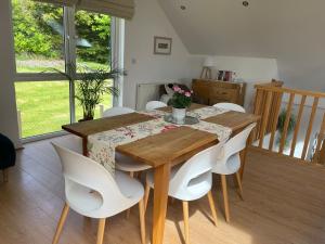 a dining room with a wooden table and white chairs at Loughview Lodge in Whitehead