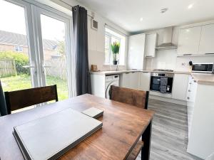 uma cozinha com uma mesa de madeira com cadeiras e uma grande janela em Wallis House by Blue Skies Stays em Stockton-on-Tees