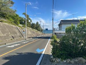 uma estrada vazia com um edifício e o oceano em Azukiya em Hanabuchihama