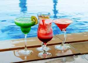 drei Cocktails auf einem Tisch neben einem Pool in der Unterkunft Centro Al Manhal by Rotana in Abu Dhabi