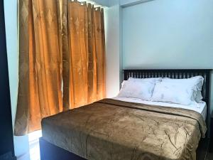 a bedroom with a bed with orange curtains at Cozy studio unit in Boracay Newcoast in Boracay