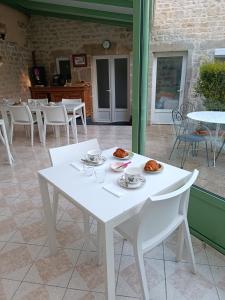 a white table with plates of food on it at Chambres d'h&ocirc;tes de l'Eglise in Sainte-M&egrave;re-&Eacute;glise