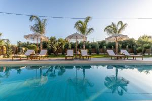 a swimming pool with lounge chairs and umbrellas at White Stone Villa Hesperia - Poolside Escape Close to Laganas Beach in Lithakia