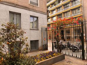 a building with a gate with flowers in front of it at San Babila Design Apartment R&R in Milan