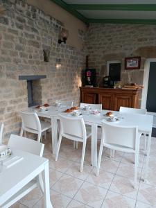 a dining room with white tables and white chairs at Chambres d'h&ocirc;tes de l'Eglise in Sainte-M&egrave;re-&Eacute;glise