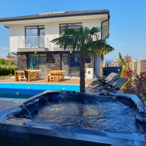 a pool with a palm tree in front of a house at Capitan Niko Apartments in Burgas City