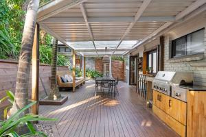 an outdoor deck with a kitchen and a table at 5 bedroom Terrigal beach home with district views in Terrigal