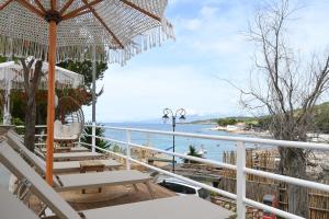 a balcony with chairs and an umbrella and the ocean at EMAAR Hotel Ksamil - BEACHFRONT , Newly Renovated in Ksamil