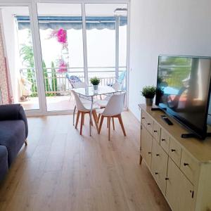 a living room with a television and a table and chairs at appartement lumineux piscine plage 250m centre ville grande terrasse portaventura in Cambrils +25 photos