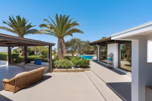 an outdoor patio with palm trees and a swimming pool at Cala Mancina in San Vito lo Capo