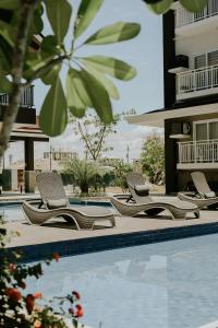 a row of lounge chairs next to a swimming pool at Amani Grand #332, Near Mactan Airport,Fast WIFI, Netflix & Pool in Pusok