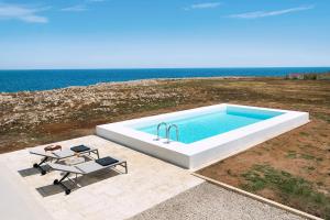 einen großen Pool mit einem Tisch und Stühlen sowie das Meer in der Unterkunft Villa Capo Passero in Portopalo