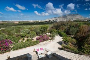 een uitzicht op een tuin met roze stoelen en bloemen bij Corte del Sale in Paceco +18 foto's