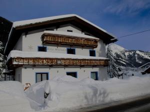 a building covered in snow in front of a mountain at Apartment with a shared sauna in Bichlbach in Bichlbach