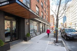 a woman walking down a sidewalk in front of a store at Blueground East Village elev wd near park NYC-1462 in New York